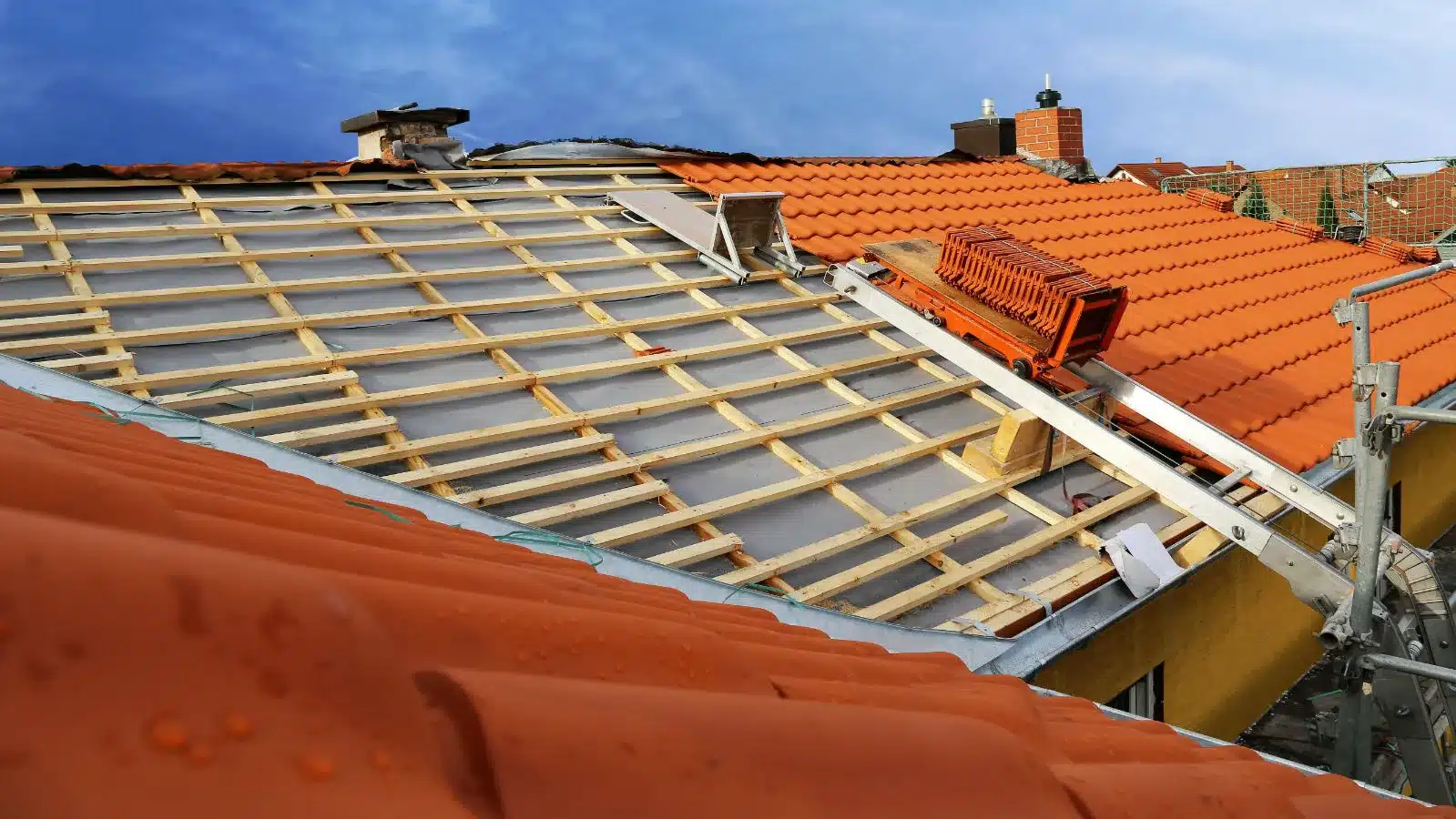 Vue d'ensemble d'un chantier de remplacement de toiture, 38, dans les Hauts-de-Seine, on voit un monte-charge qui met permet de la pose de tuiles sur la toiture